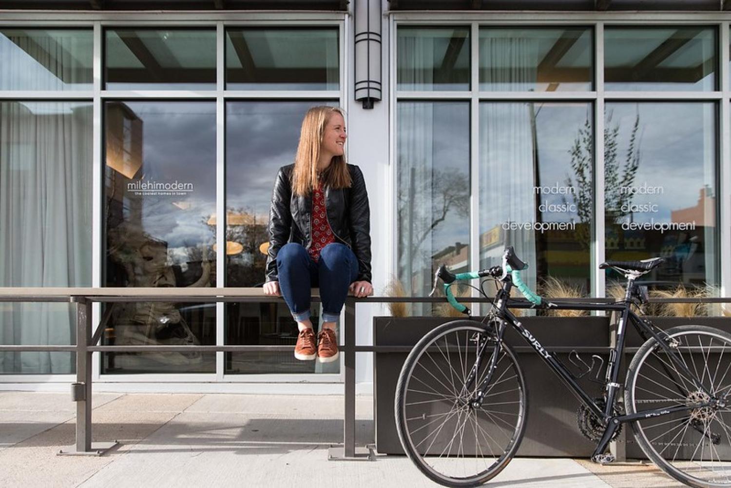 Woman sitting on railing next to bike