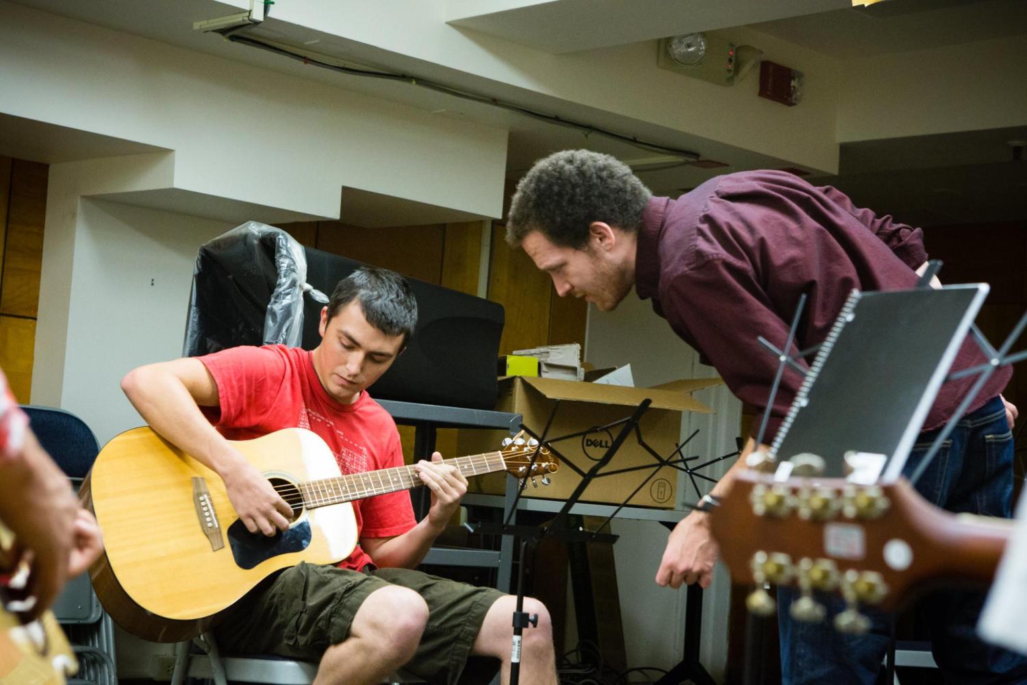 A student receives feedback on his guitar playing from his instructor