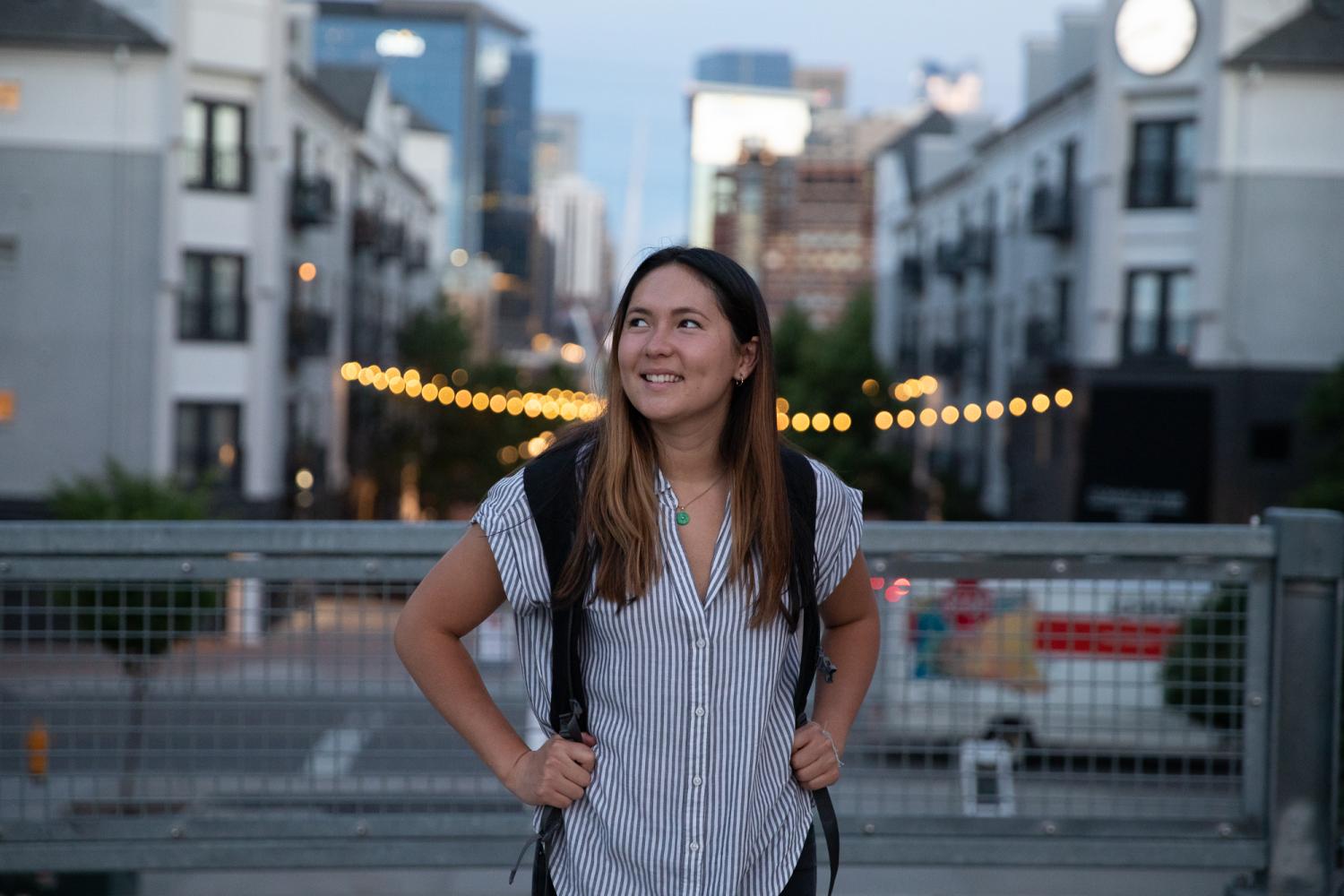A student wearing a backpack smiles as she poses outside in Denver