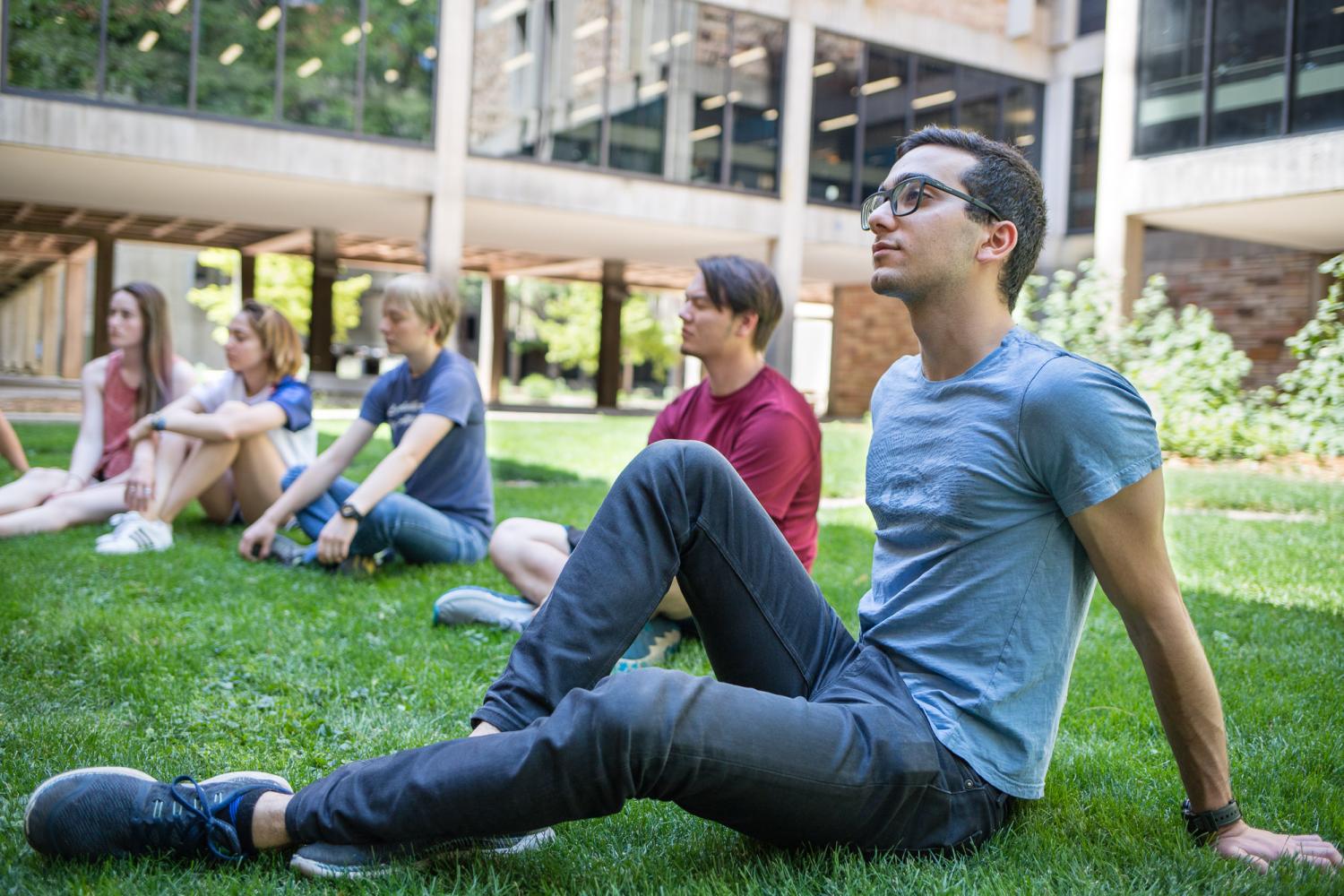 A group of students reclines on the grass outside on campus