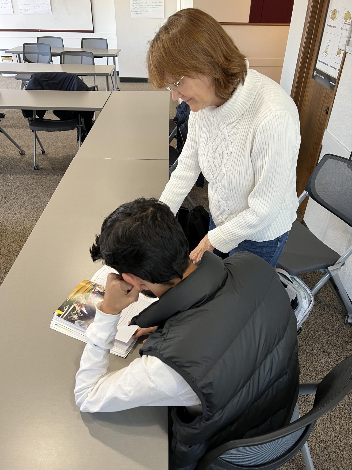 woman instructs student over textbook