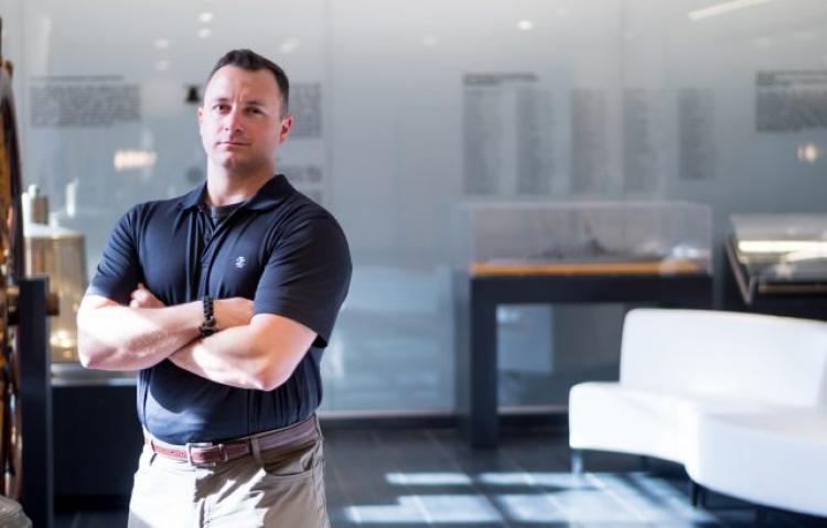 Man in navy polo standing in building with glass walls