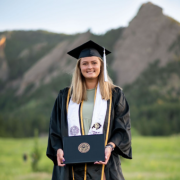 blonde student wearing graduation cap and gown holding diploma and standing in front of mountain; Google document that Amanda got feedback on